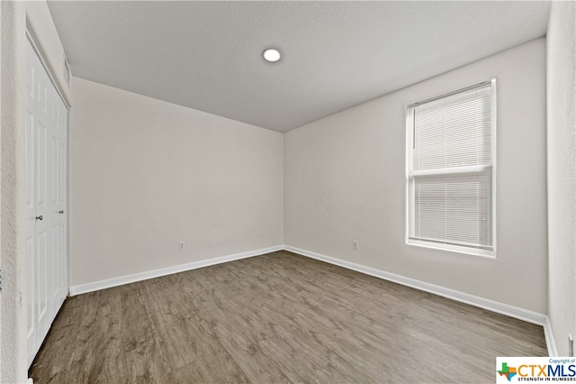 spare room featuring hardwood / wood-style floors and a textured ceiling