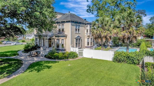 rear view of house featuring a lawn and a fenced in pool