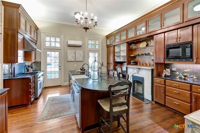 kitchen with a high end fireplace, appliances with stainless steel finishes, pendant lighting, an inviting chandelier, and an AC wall unit