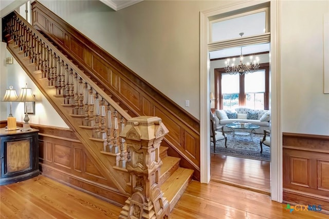 stairs featuring hardwood / wood-style floors, an inviting chandelier, and ornamental molding