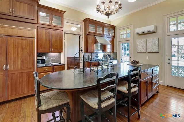 dining space with a wall mounted AC, sink, a chandelier, and light hardwood / wood-style floors