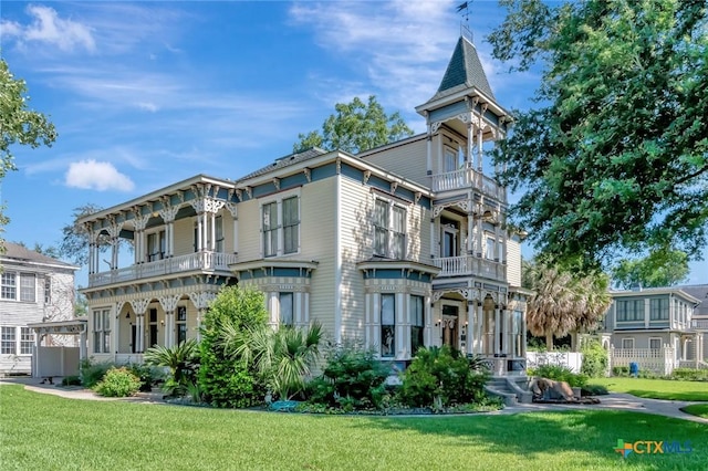 view of front of property featuring a balcony and a front lawn