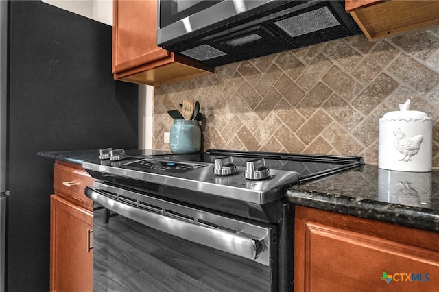 kitchen featuring decorative backsplash, stainless steel range with gas stovetop, and dark stone counters