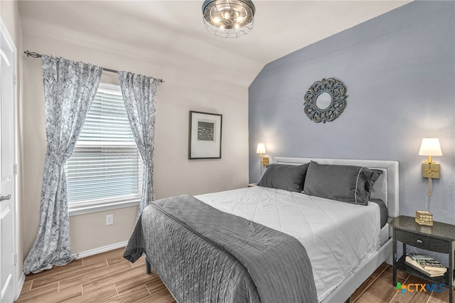 bedroom featuring hardwood / wood-style floors, multiple windows, and vaulted ceiling