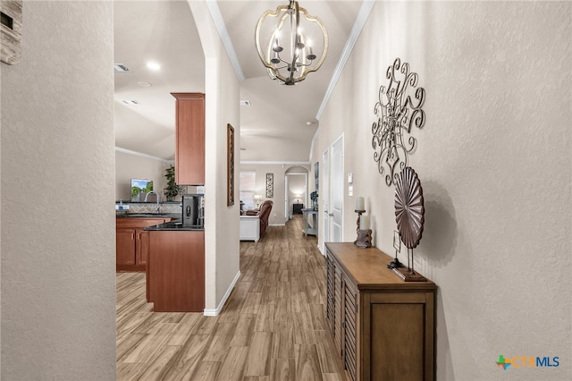 entrance foyer with light hardwood / wood-style flooring, sink, crown molding, and an inviting chandelier