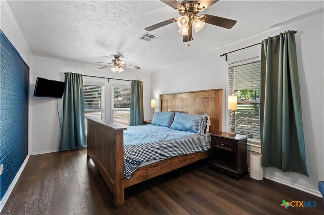 4007 Austin Ave, Waco, TX 76710 - bedroom with multiple windows, dark wood finished floors, brick wall, a ceiling fan, and a textured ceiling