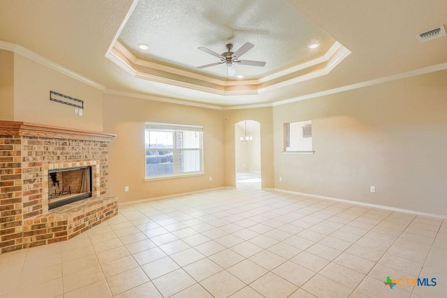 unfurnished living room featuring ceiling fan, a tray ceiling, ornamental molding, and light tile patterned flooring