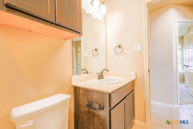 bathroom with toilet, vanity, and tile patterned flooring