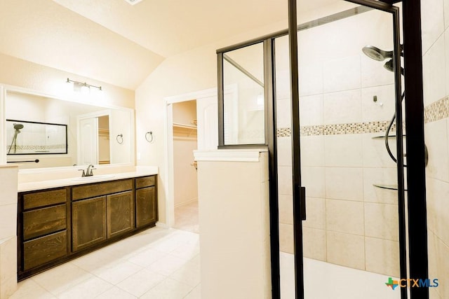 bathroom featuring vaulted ceiling, tile patterned floors, walk in shower, and vanity