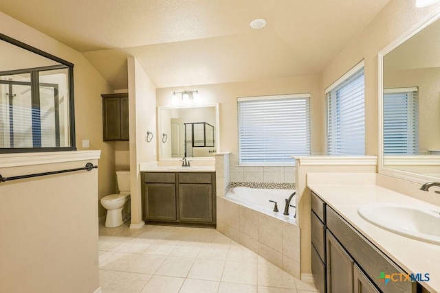 bathroom with lofted ceiling, tile patterned floors, vanity, toilet, and tiled bath