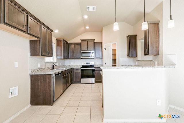 kitchen with lofted ceiling, stainless steel appliances, decorative backsplash, hanging light fixtures, and light stone counters