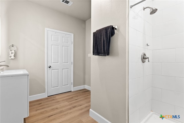 bathroom featuring vanity, wood-type flooring, and tiled shower