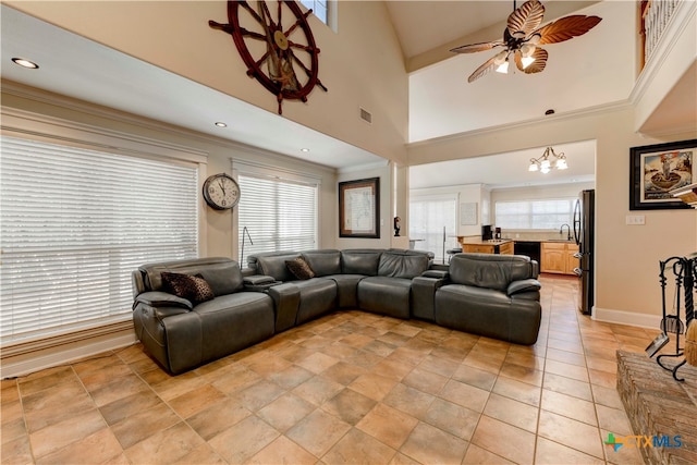 living room with ceiling fan with notable chandelier, a towering ceiling, and crown molding