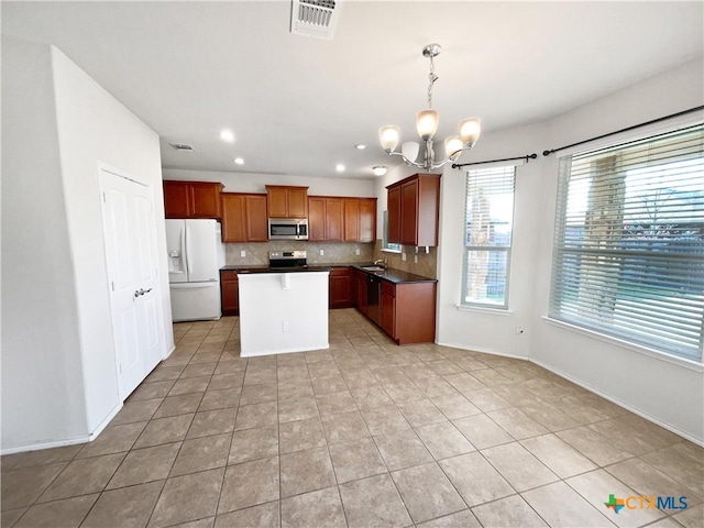 kitchen with decorative light fixtures, light tile patterned floors, appliances with stainless steel finishes, a notable chandelier, and a kitchen island