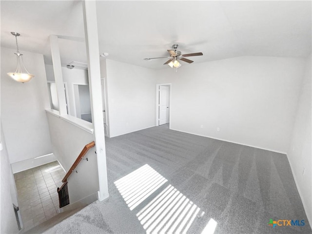 empty room featuring ceiling fan, vaulted ceiling, and dark colored carpet