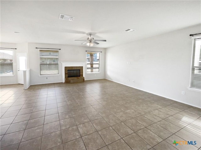 unfurnished living room featuring a fireplace, ceiling fan, and tile patterned flooring