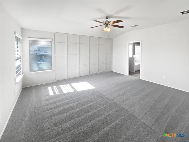 empty room with ceiling fan, dark carpet, and lofted ceiling