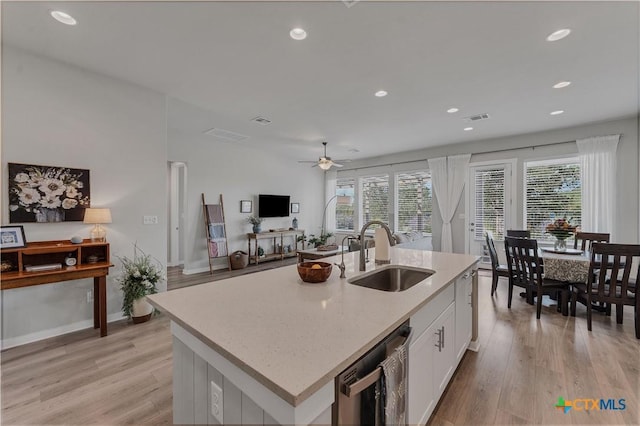 kitchen with a center island with sink, light wood-type flooring, white cabinets, sink, and black dishwasher