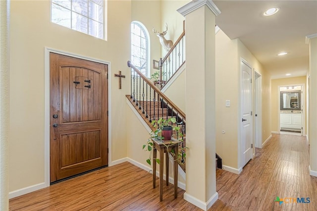 entryway with recessed lighting, wood finished floors, baseboards, and decorative columns