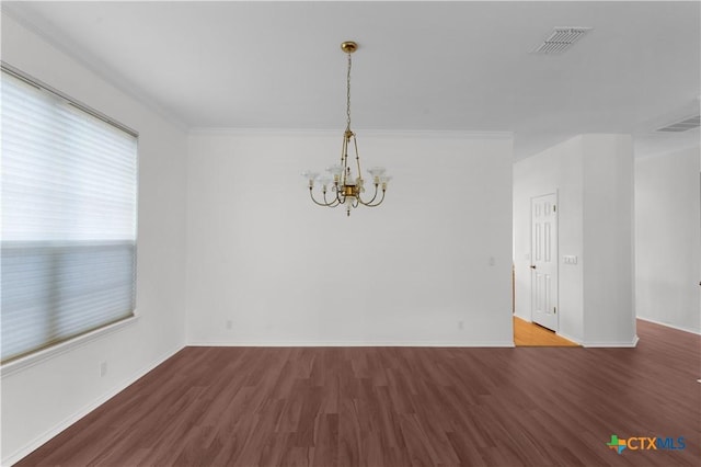 spare room featuring a chandelier, hardwood / wood-style flooring, and crown molding