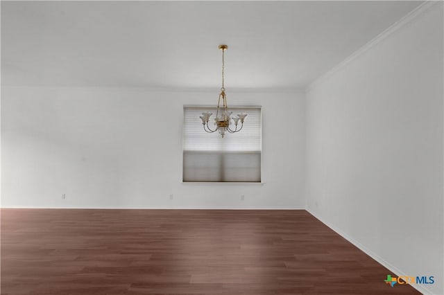 spare room featuring dark hardwood / wood-style floors, ornamental molding, and a chandelier