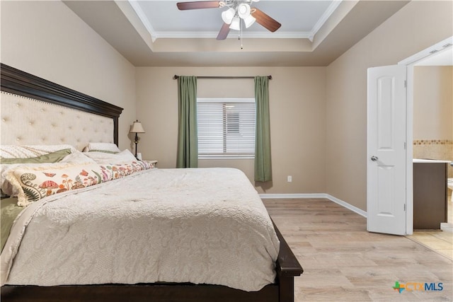 bedroom with ornamental molding, baseboards, light wood-type flooring, a tray ceiling, and a ceiling fan