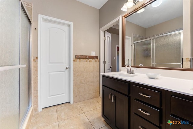 full bath with tile walls, a stall shower, vanity, tile patterned floors, and a wainscoted wall