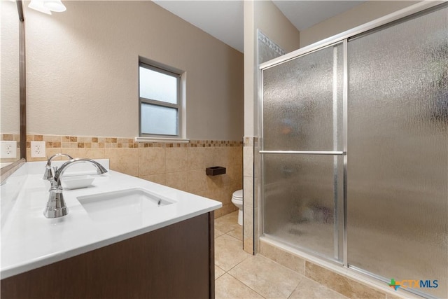 bathroom featuring tile walls, a stall shower, a sink, tile patterned floors, and toilet
