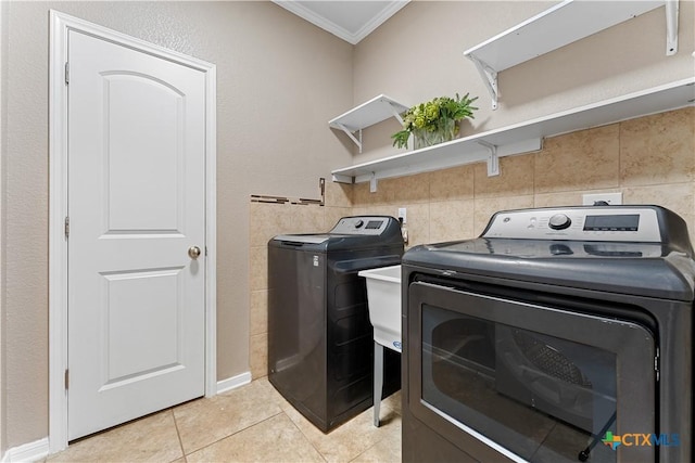 laundry area featuring laundry area, tile walls, light tile patterned floors, ornamental molding, and washer and dryer