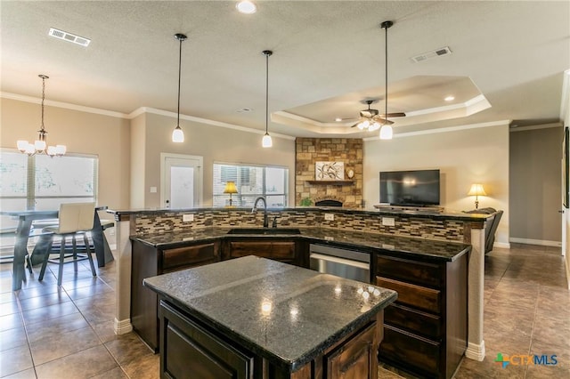 kitchen with a large island, visible vents, a tray ceiling, and a sink