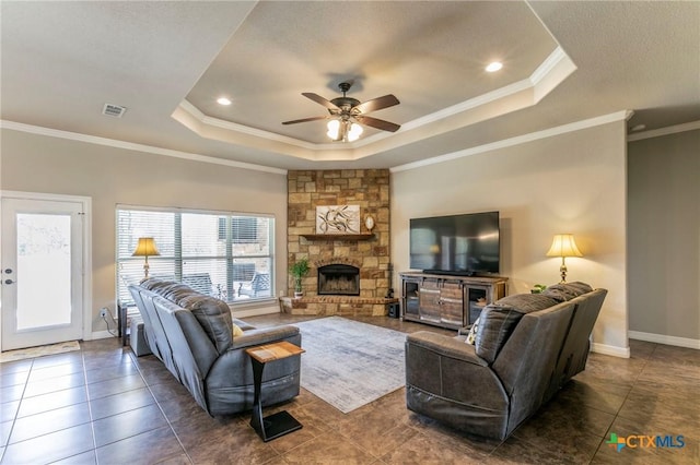 living room with a tray ceiling, a ceiling fan, baseboards, and ornamental molding