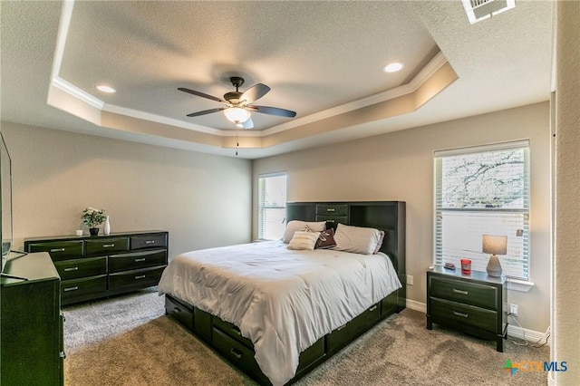 carpeted bedroom with a tray ceiling, a textured ceiling, visible vents, and crown molding