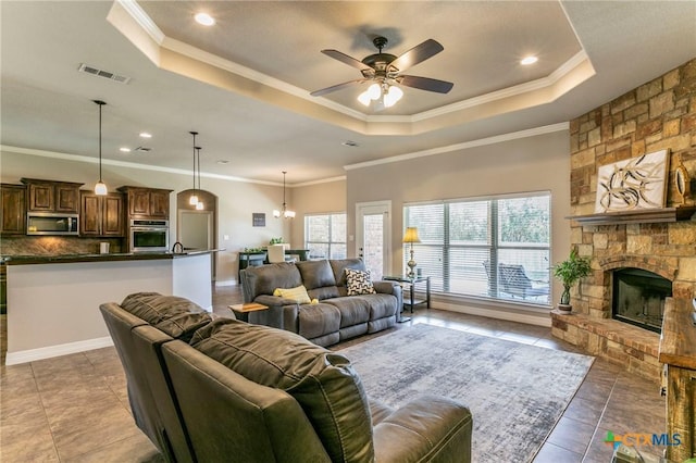 tiled living room featuring a wealth of natural light, a ceiling fan, and a tray ceiling