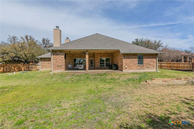 back of property featuring a lawn, a patio area, fence, and a chimney