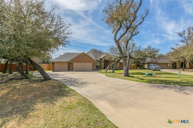 ranch-style home featuring a front yard, fence, concrete driveway, a garage, and brick siding