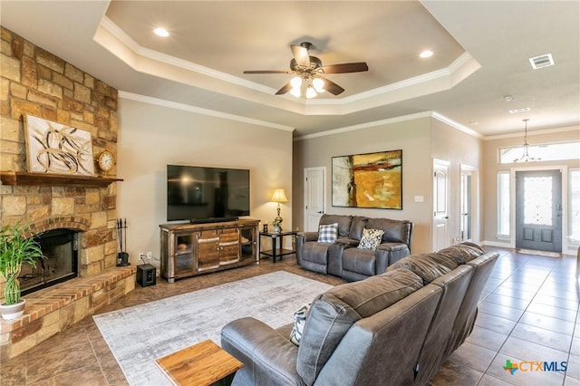 tiled living room featuring visible vents, a fireplace, ornamental molding, ceiling fan, and a raised ceiling