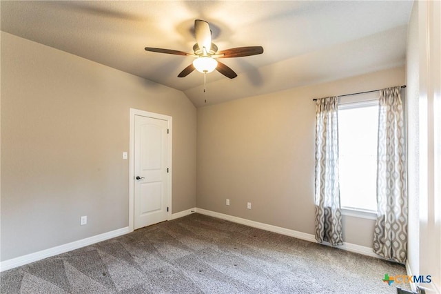 carpeted spare room featuring baseboards, plenty of natural light, lofted ceiling, and a ceiling fan