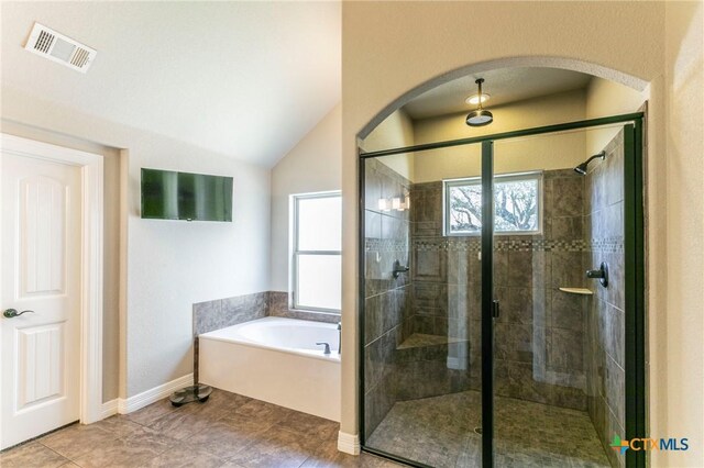 bathroom featuring visible vents, a stall shower, baseboards, a bath, and vaulted ceiling