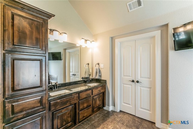 full bathroom featuring vaulted ceiling, double vanity, visible vents, and a sink