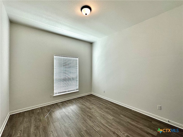 unfurnished room with dark wood-type flooring