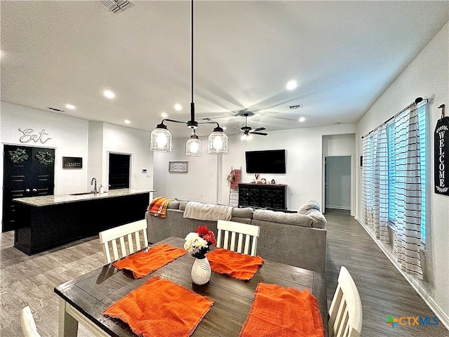 dining space featuring sink, wood-type flooring, and ceiling fan