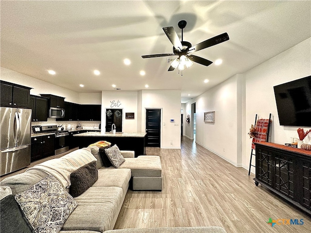 living room with a textured ceiling, light hardwood / wood-style flooring, and ceiling fan