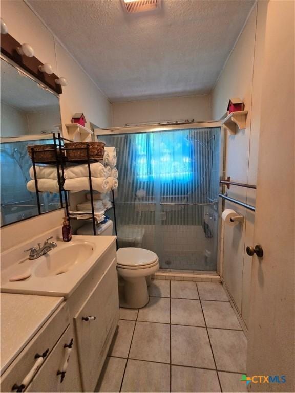 bathroom with a textured ceiling, tile patterned flooring, a shower stall, vanity, and toilet