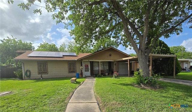 single story home with a front yard, a carport, a garage, roof mounted solar panels, and concrete driveway