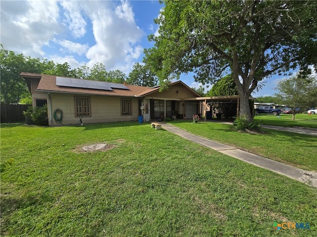 ranch-style home featuring a front lawn, roof mounted solar panels, and fence