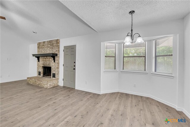 2316 Schwertner Dr, Killeen, TX 76543 - unfurnished living room featuring wood finished floors, a chandelier, a textured ceiling, and a brick fireplace