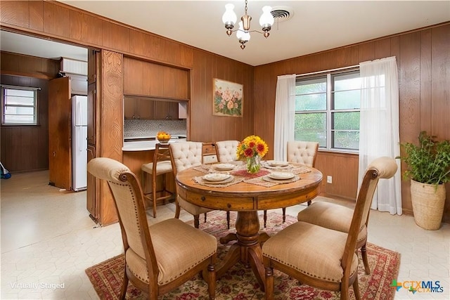 dining room featuring wood walls and a notable chandelier