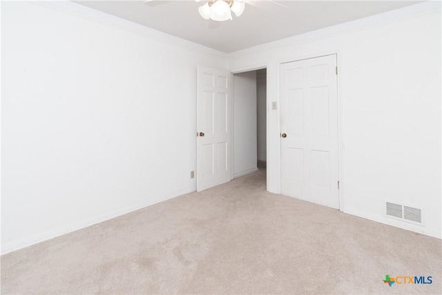 spare room with ceiling fan, crown molding, and light carpet