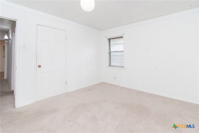 unfurnished bedroom with light colored carpet, a closet, and crown molding