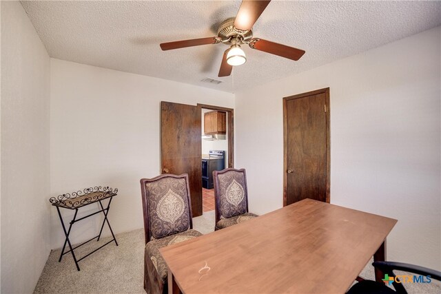 carpeted dining room with ceiling fan and a textured ceiling